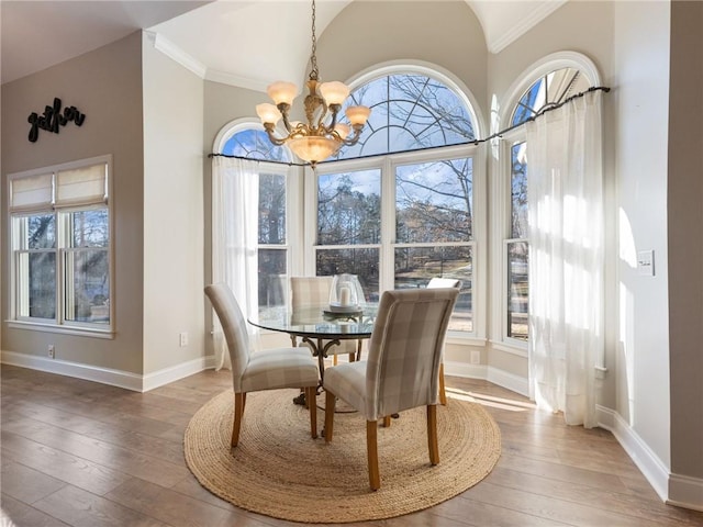 dining space with lofted ceiling, an inviting chandelier, ornamental molding, and hardwood / wood-style flooring