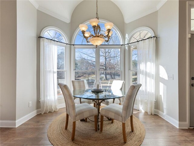 dining space with vaulted ceiling, a wealth of natural light, wood-type flooring, and a notable chandelier