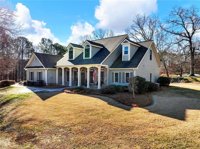 cape cod home featuring covered porch and a front lawn