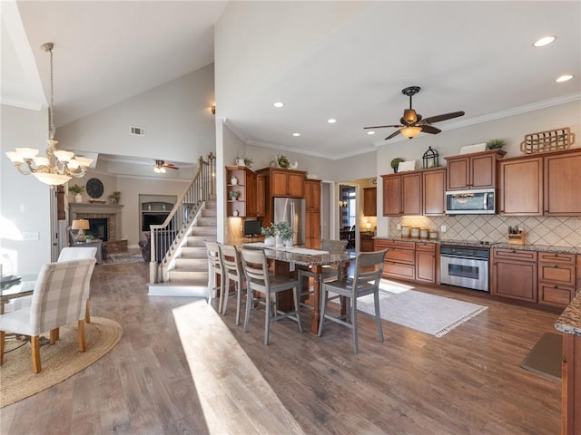 dining space featuring ceiling fan with notable chandelier, dark wood-type flooring, and crown molding