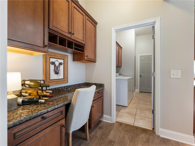 kitchen featuring light hardwood / wood-style flooring, built in desk, washer and clothes dryer, and dark stone countertops