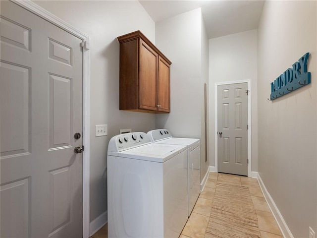 laundry room featuring washing machine and dryer, light tile patterned flooring, and cabinets