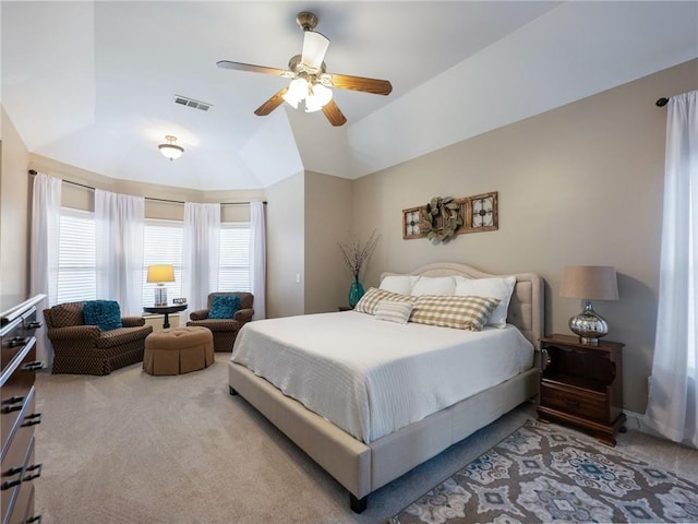 carpeted bedroom with ceiling fan, vaulted ceiling, and a tray ceiling