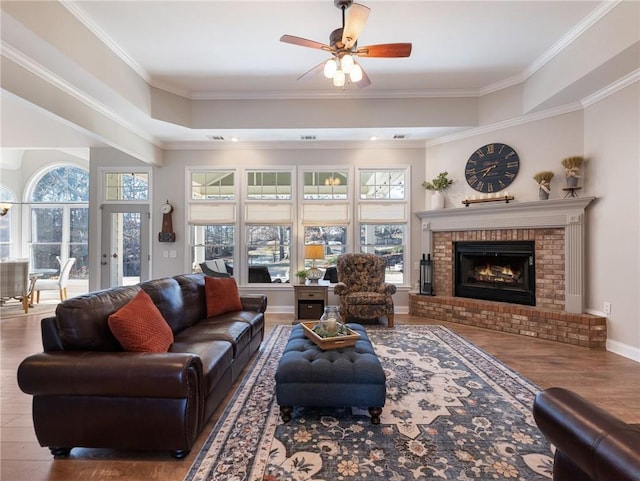 living room featuring ceiling fan, a fireplace, ornamental molding, and hardwood / wood-style floors