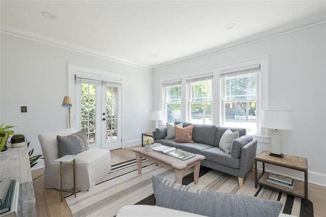 living room with french doors, ornamental molding, and light wood-type flooring