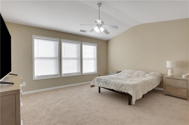 bedroom with lofted ceiling, light colored carpet, visible vents, and baseboards