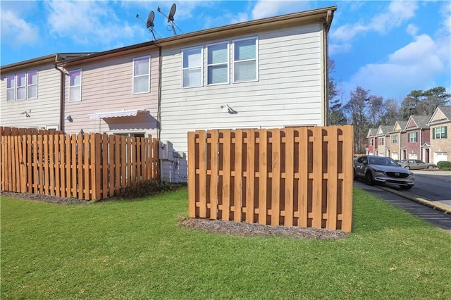 rear view of house with a residential view, a lawn, and fence