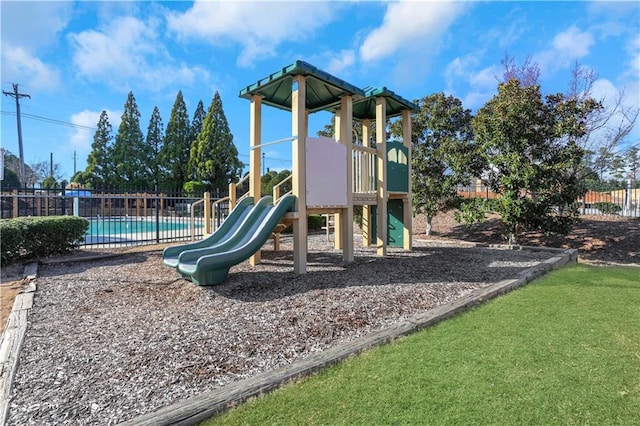 community jungle gym featuring fence and a fenced in pool