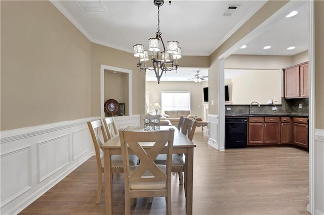 dining area featuring visible vents, a decorative wall, ornamental molding, and light wood-style flooring