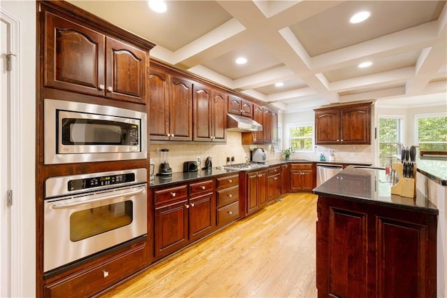 kitchen featuring stainless steel appliances, under cabinet range hood, light wood-style flooring, backsplash, and beam ceiling
