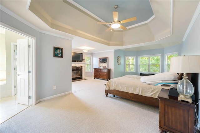 bedroom with a tray ceiling, a high end fireplace, carpet floors, ornamental molding, and baseboards