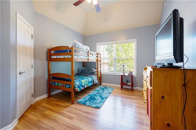 bedroom with light wood finished floors, lofted ceiling, baseboards, and ceiling fan