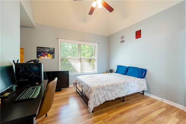 bedroom featuring light wood finished floors, baseboards, a ceiling fan, and a desk