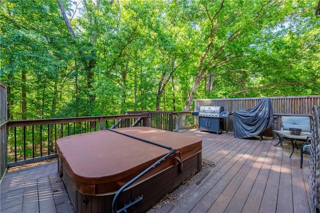 wooden deck featuring a covered hot tub and a grill