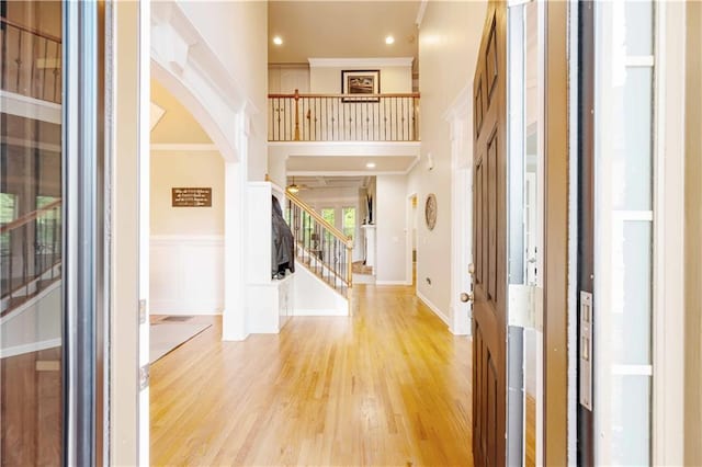 entrance foyer with stairs, ornamental molding, arched walkways, wood finished floors, and recessed lighting
