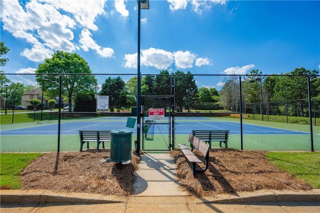 view of tennis court with a gate and fence