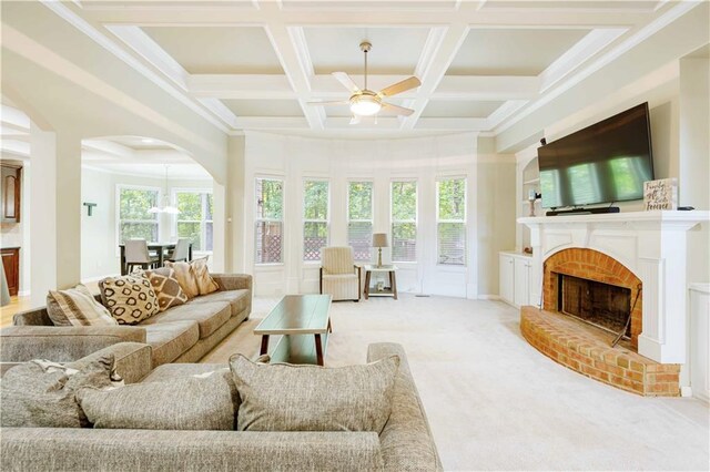 living room with ceiling fan, arched walkways, coffered ceiling, carpet, and a brick fireplace