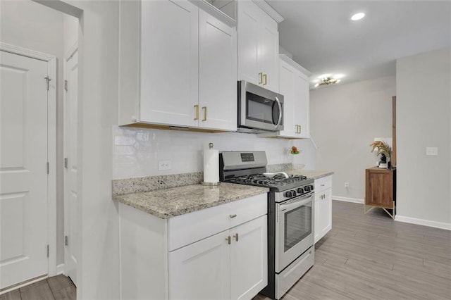 1969 Lanier Harbor Pt, Buford, GA 30518 - kitchen with stainless steel appliances, white cabinetry, light stone countertops, tasteful backsplash, and light wood-style flooring