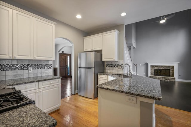 kitchen featuring sink, stainless steel fridge, dark stone counters, and white cabinets