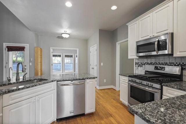 kitchen with backsplash, stainless steel appliances, sink, and white cabinets