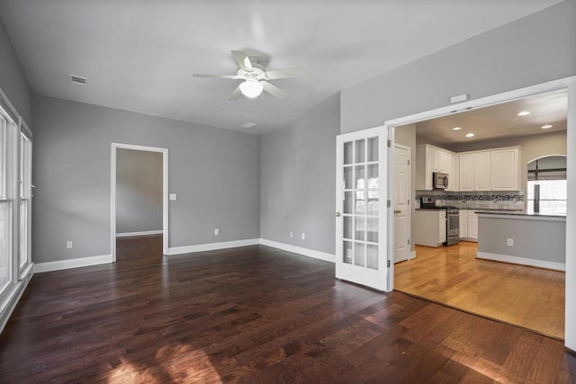 unfurnished living room featuring dark wood-type flooring, ceiling fan, and french doors