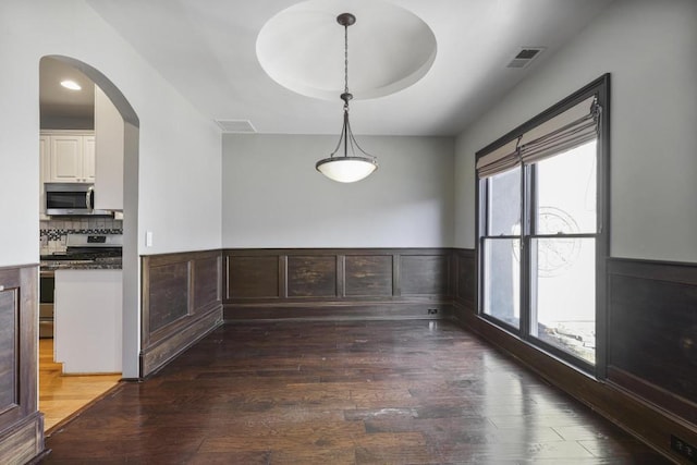 unfurnished dining area with a tray ceiling and dark hardwood / wood-style flooring