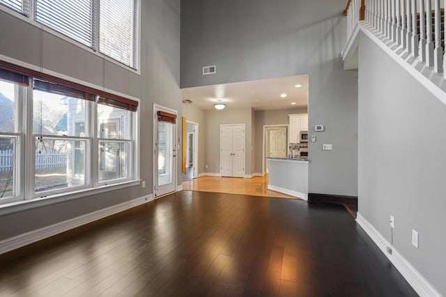 unfurnished living room with hardwood / wood-style flooring and a towering ceiling