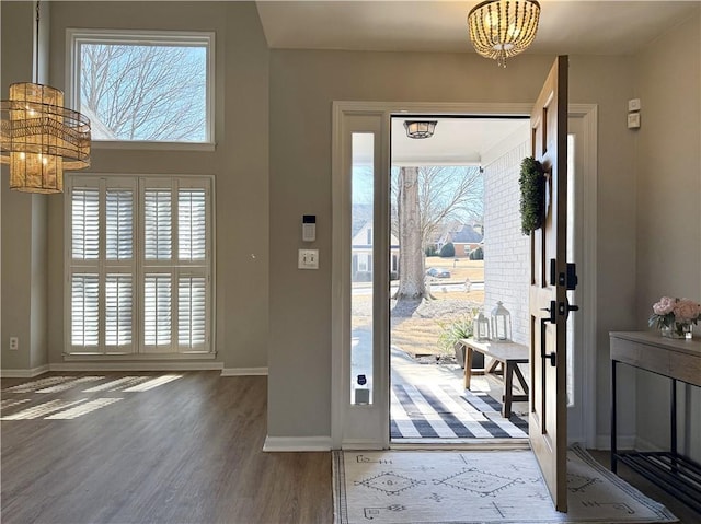 entrance foyer featuring a chandelier, baseboards, and wood finished floors