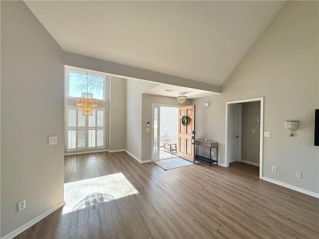 interior space with high vaulted ceiling, wood finished floors, baseboards, and an inviting chandelier