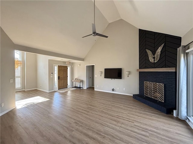 unfurnished living room featuring baseboards, a ceiling fan, wood finished floors, a fireplace, and high vaulted ceiling