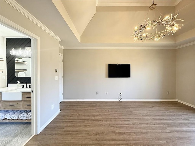 unfurnished living room with a chandelier, a tray ceiling, baseboards, and wood finished floors