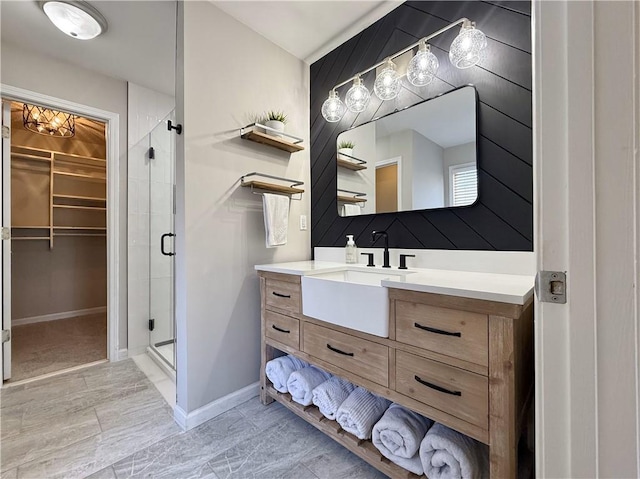 bathroom featuring a spacious closet, a stall shower, vanity, and baseboards