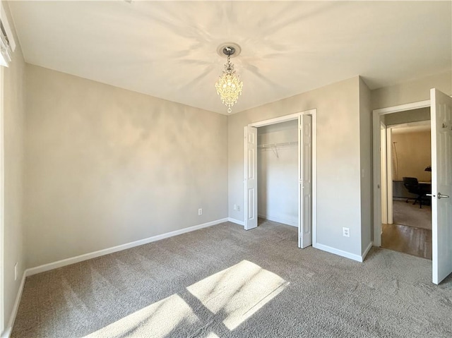 unfurnished bedroom featuring light carpet, a notable chandelier, baseboards, and a closet