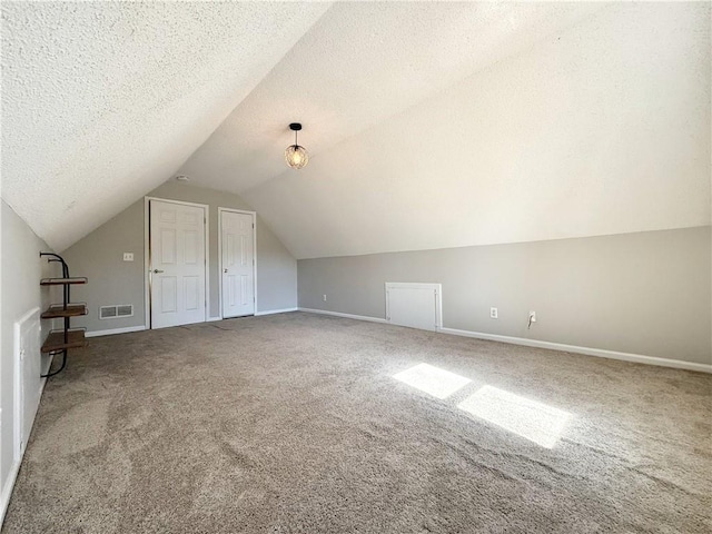 bonus room featuring carpet floors, lofted ceiling, visible vents, and a textured ceiling