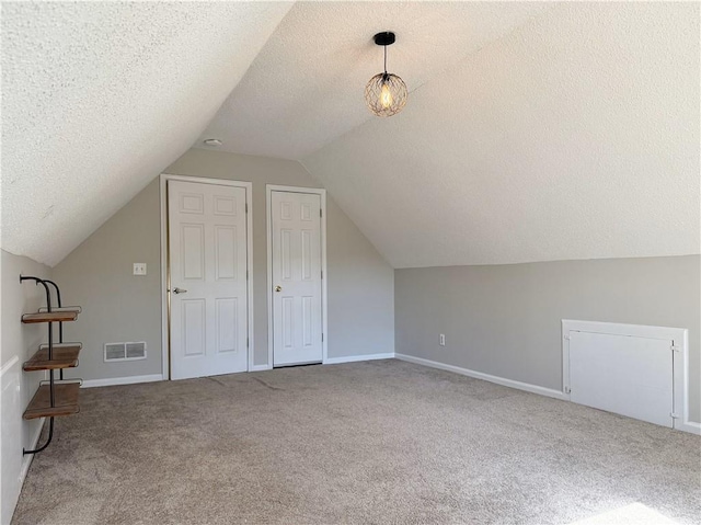 additional living space with lofted ceiling, visible vents, a textured ceiling, and carpet flooring