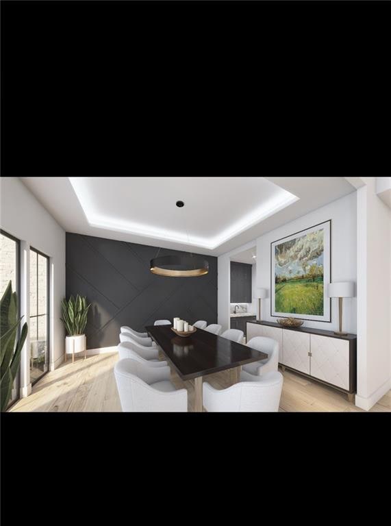 dining area with light wood finished floors and a raised ceiling