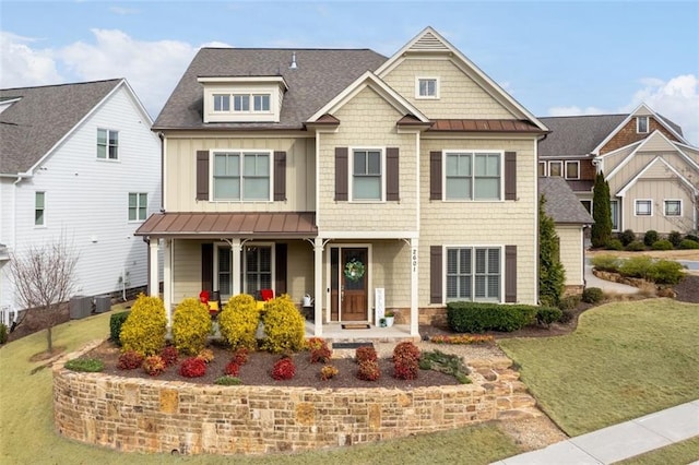 craftsman inspired home featuring a porch, cooling unit, and a front lawn