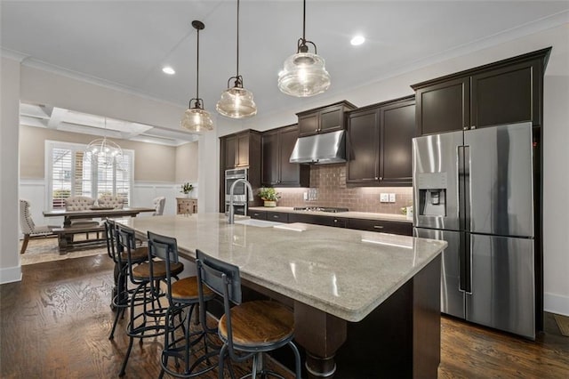 kitchen featuring hanging light fixtures, appliances with stainless steel finishes, a breakfast bar area, and a center island with sink