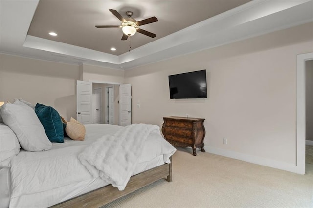 carpeted bedroom with ceiling fan and a tray ceiling