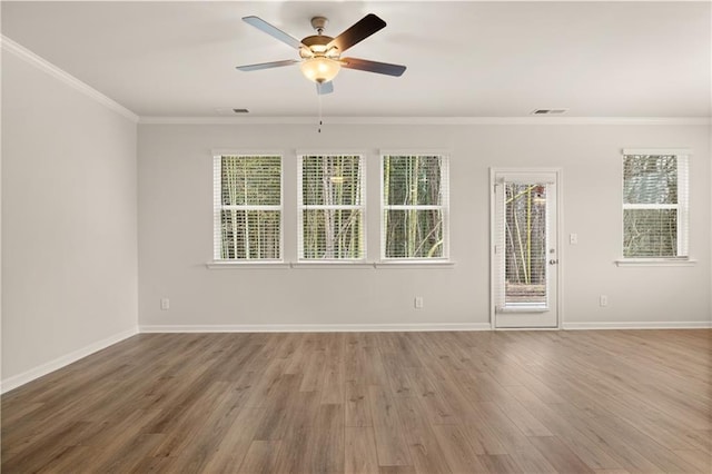 spare room featuring baseboards, plenty of natural light, ornamental molding, and wood finished floors