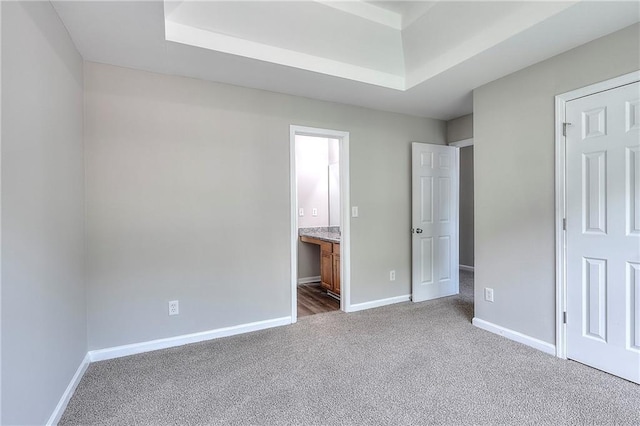 4041 Ash Tree St, Snellville, GA 30039 - unfurnished bedroom featuring dark colored carpet, a tray ceiling, baseboards, and ensuite bathroom