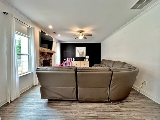 living room with crown molding, a fireplace, a ceiling fan, baseboards, and wood finished floors