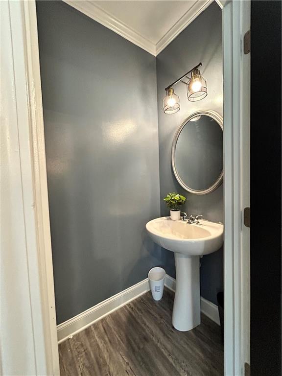 bathroom with ornamental molding, wood finished floors, baseboards, and a sink