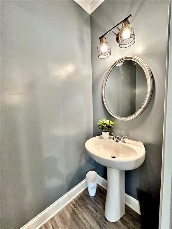 bathroom featuring wood finished floors, baseboards, and ornamental molding
