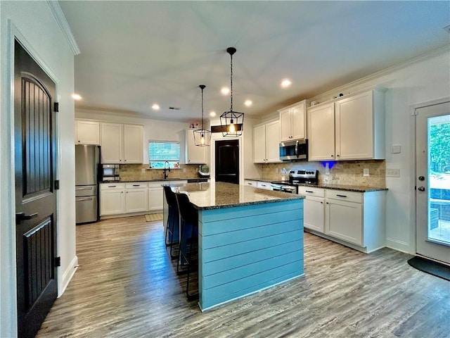kitchen with appliances with stainless steel finishes, wood finished floors, healthy amount of natural light, backsplash, and recessed lighting