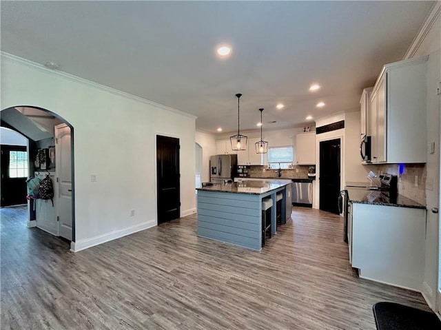 kitchen featuring stainless steel appliances, crown molding, recessed lighting, wood finished floors, and tasteful backsplash