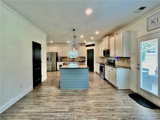 kitchen featuring stainless steel appliances, a sink, crown molding, recessed lighting, and white cabinetry