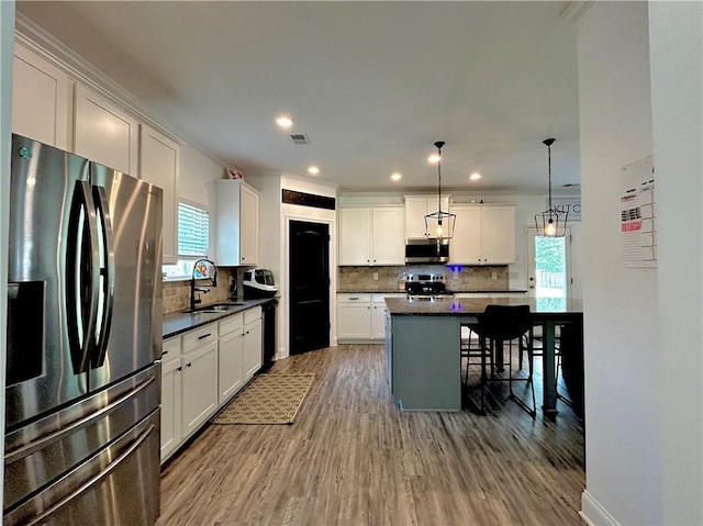 kitchen with appliances with stainless steel finishes, a sink, decorative backsplash, wood finished floors, and recessed lighting