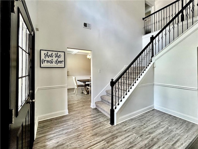 foyer with a high ceiling, stairway, wood finished floors, and baseboards
