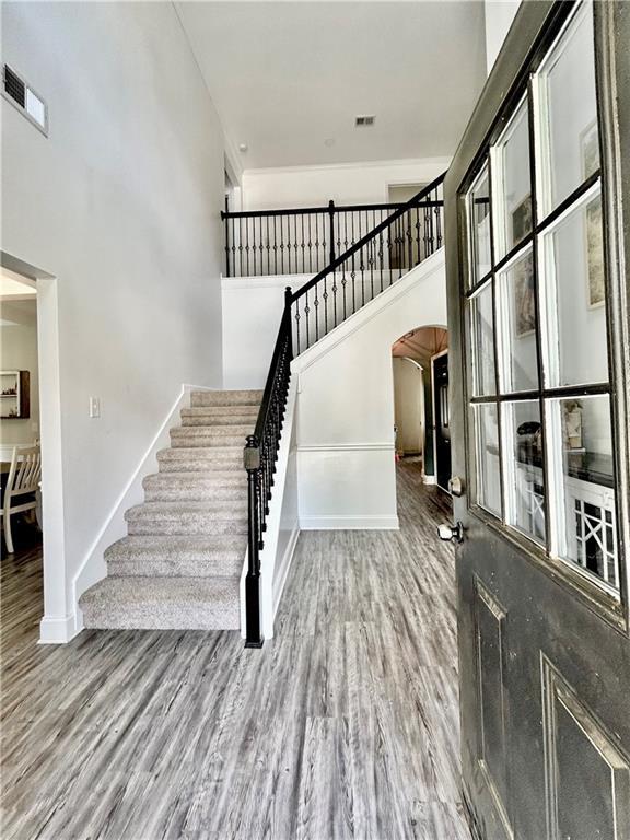 entrance foyer with arched walkways, wood finished floors, baseboards, and stairway